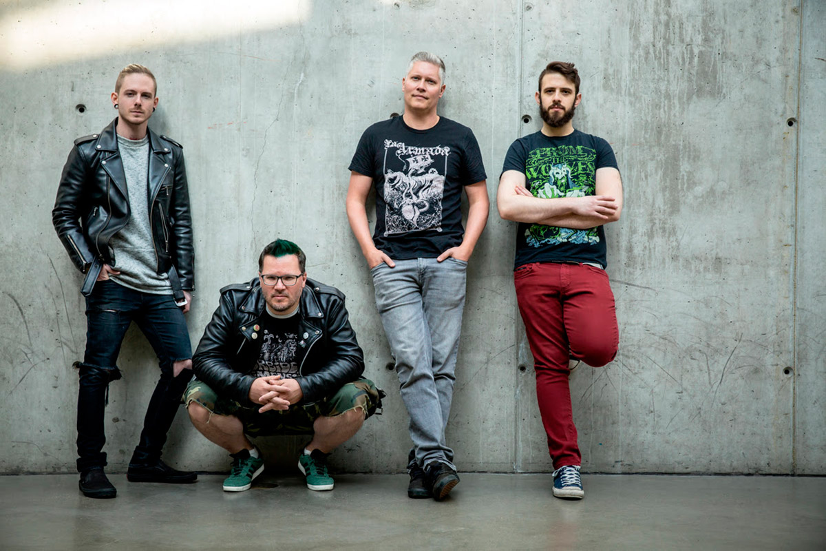 Four members of Belvedere posing against a concrete wall in a promotional band photo