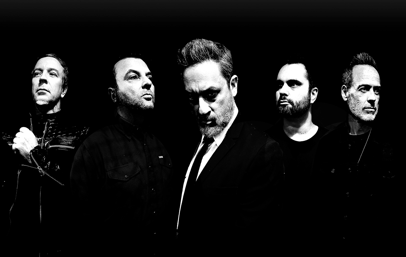 Black-and-white promotional band portrait of five members of Strung Out against a dark background