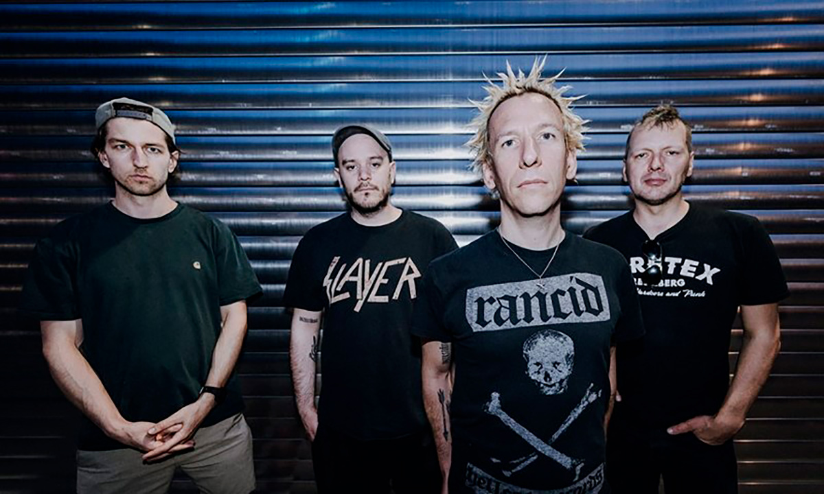 Four members of ZSK posing in front of a metal shutter in a band promo photo