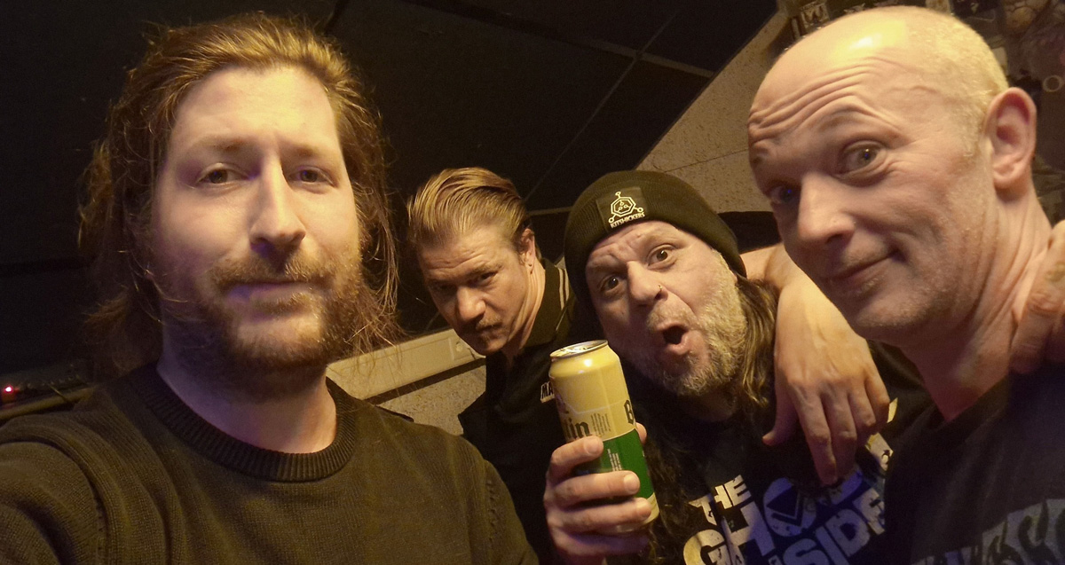 Members of Luxembourg metal band Cosmogon posing backstage for a close-up group photo before or after a live show.